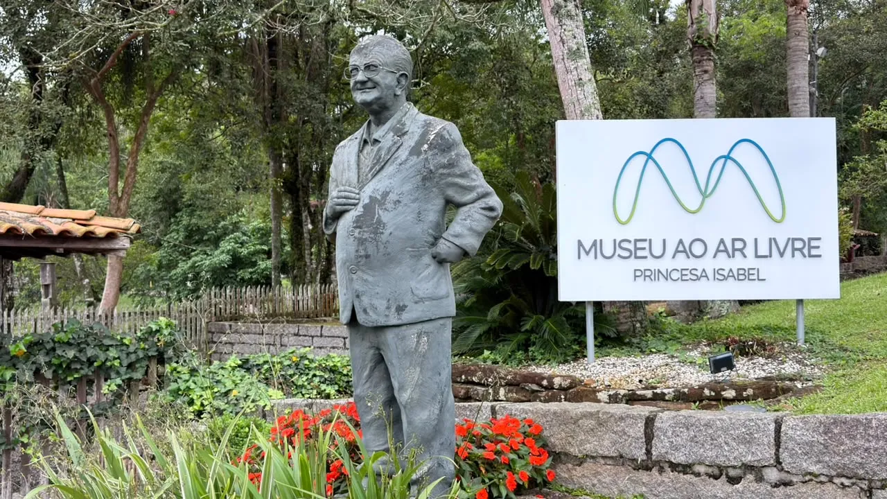 Escultura do fundador do museu ao ar livre com a placa de fundo. 